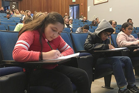 students sitting in auditorium writing