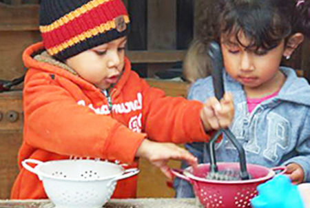 two young children playing with colanders
