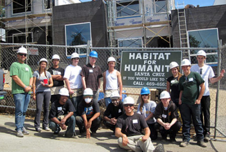 students in hardhats i front of habitat for humanity project