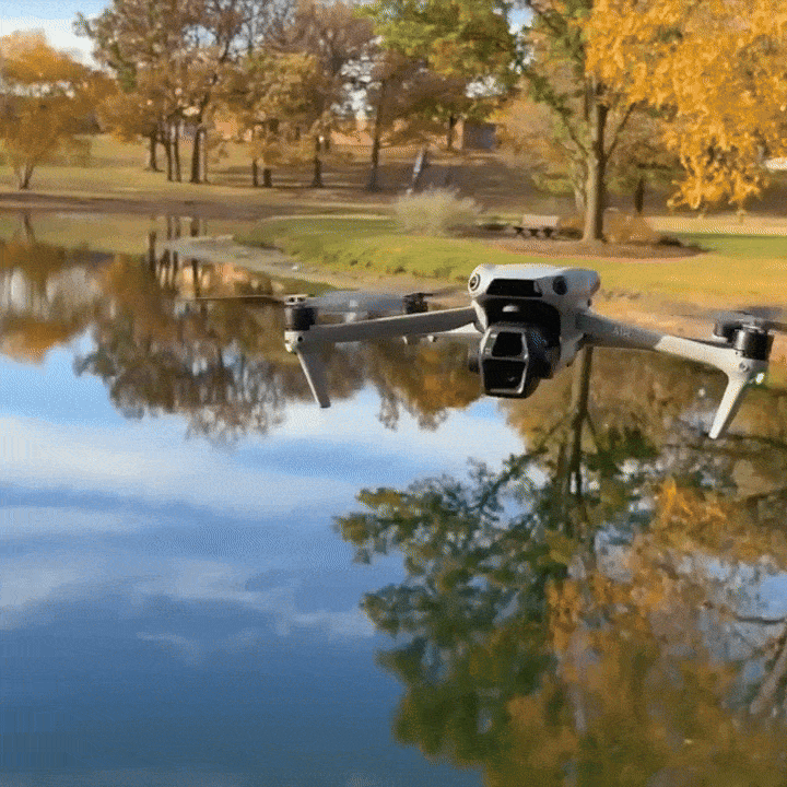 Drone flying over placid pond.